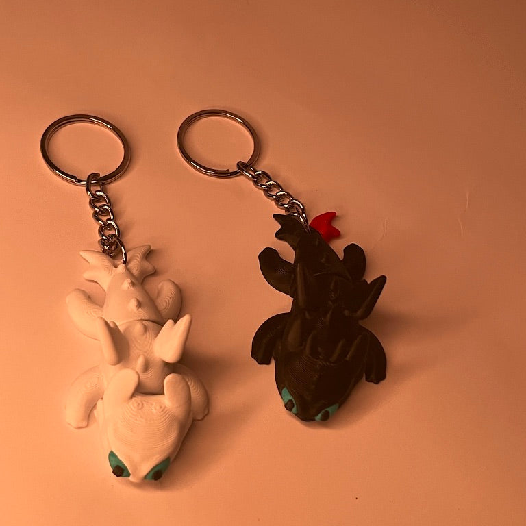 Two keychains, one white and one black, on a beige background