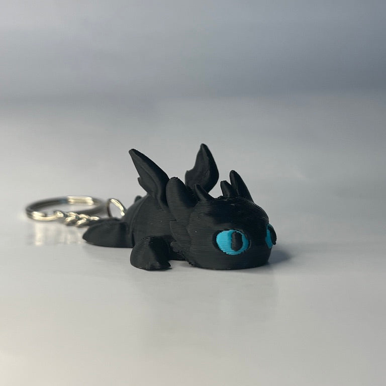 Black dragon keychain with blue eyes on a white background