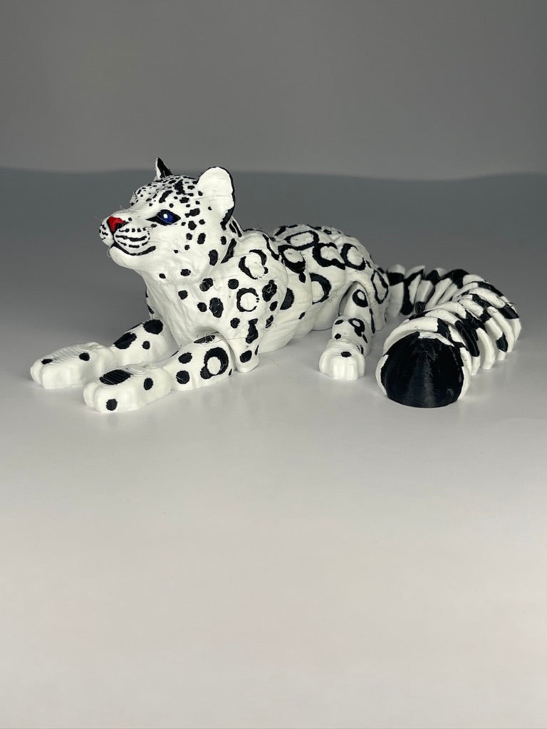 White figurine of a snow leopard with black spots on a gray background