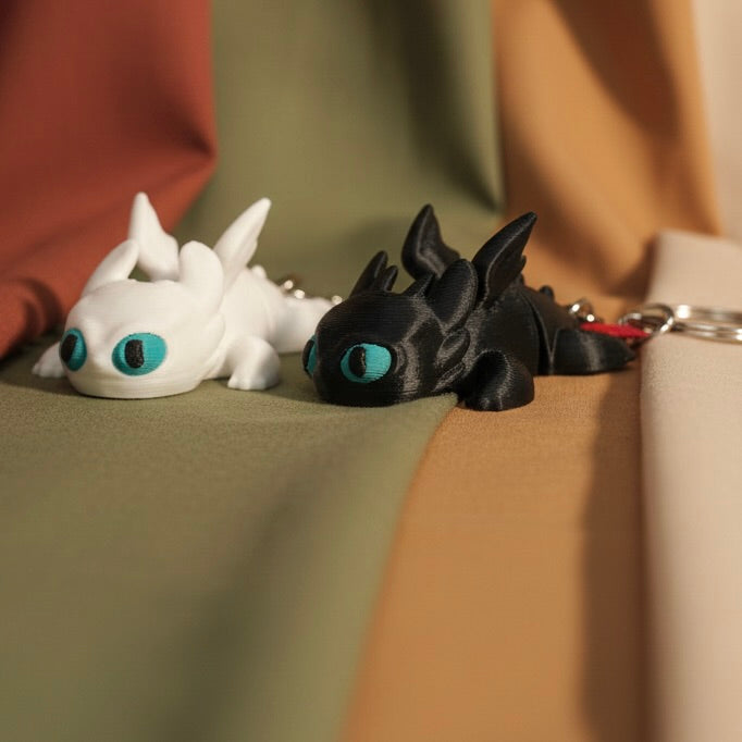 Two dragon toys, one white and one black, with blue eyes on a textured surface.