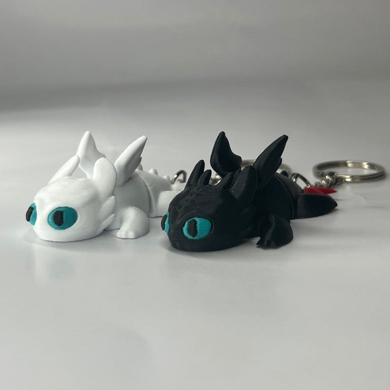 Two dragon-shaped keychains, one white and one black, on a light gray background.