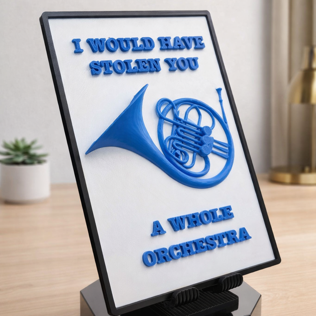 Decorative sign with a blue horn graphic and text on a white background, placed on a wooden surface.