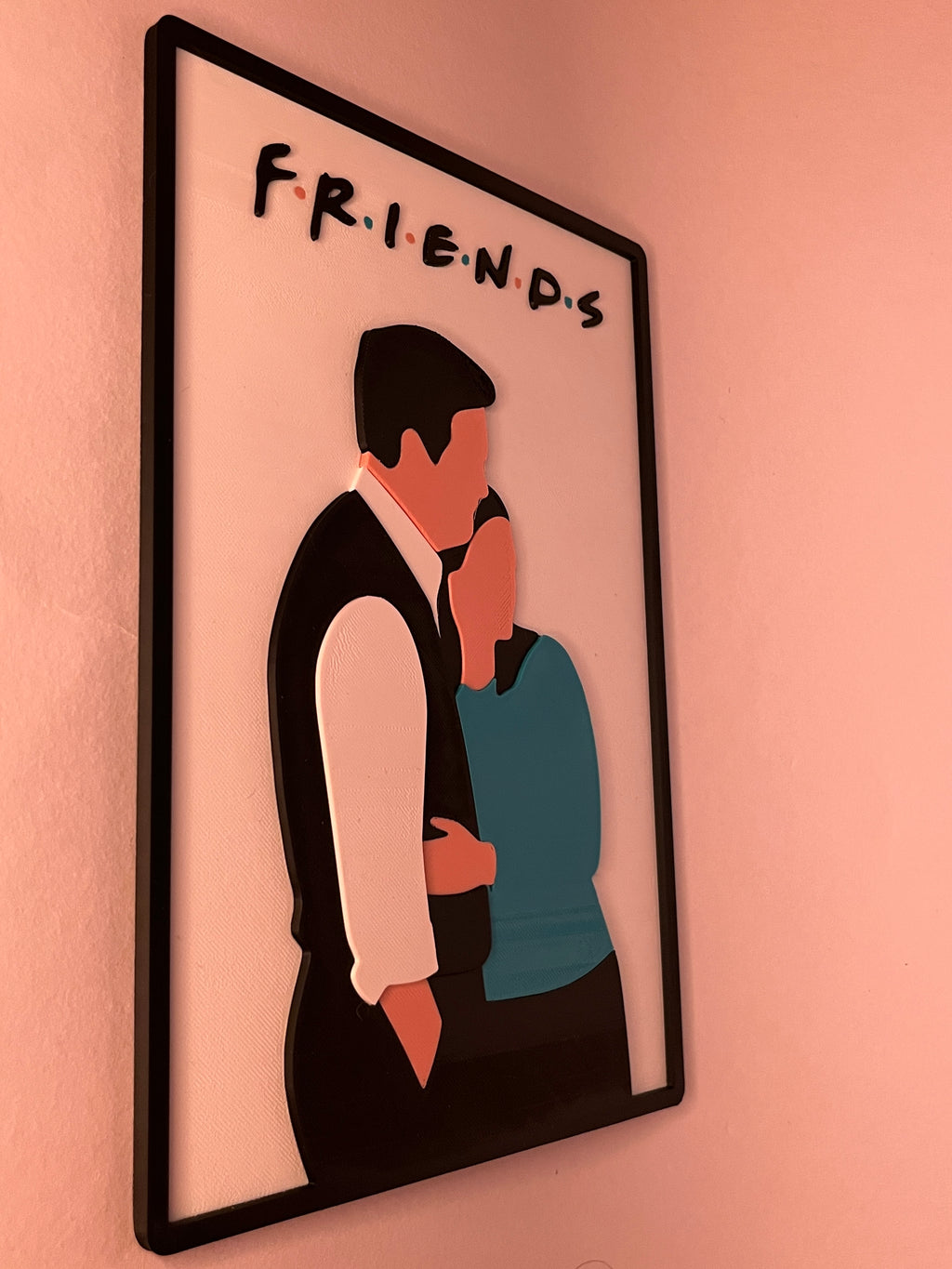 Framed artwork of two characters from 'Friends' on a pink wall.