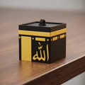Black and gold decorative box with Arabic text on a wooden surface