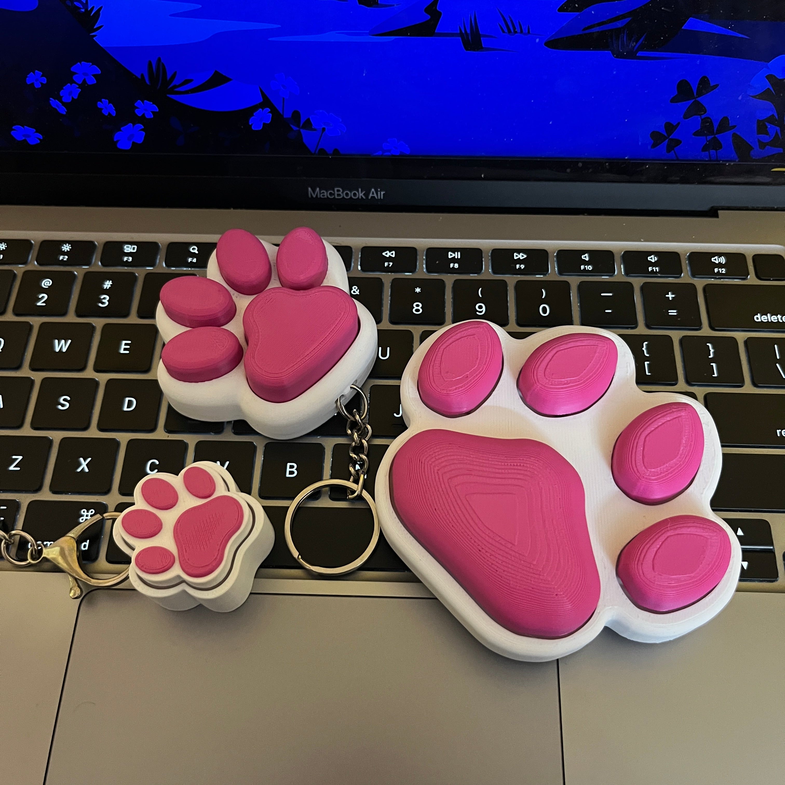 Pink paw-shaped keychain on a laptop keyboard